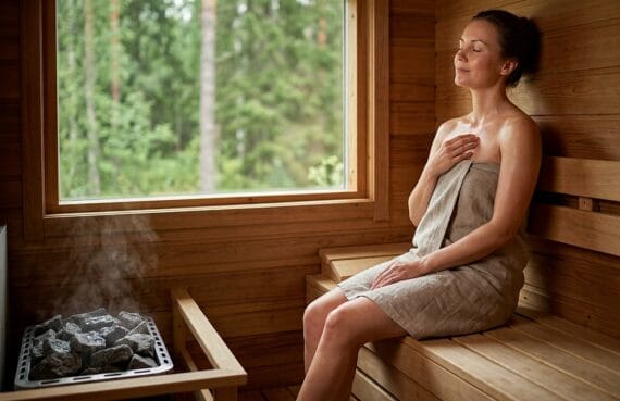 Frau entspannt in Sauna mit Blick nach draußen auf Natur.