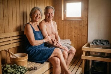 Älteres Paar entspannt in Sauna mit Holzinterieur und Fenster.